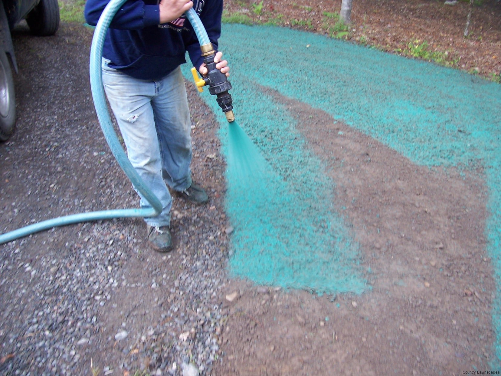 An Amazing Lawn's employee spraying hydroseeds on a yard.